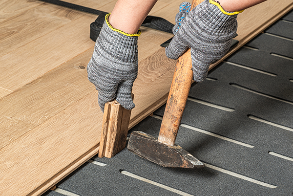 Subfloor layers being glued and nailed before hardwood installation